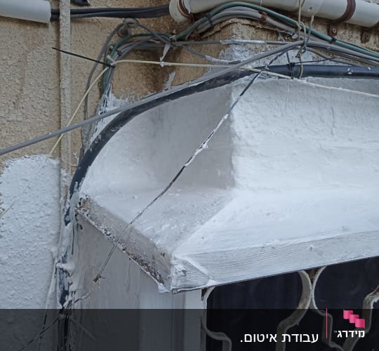 חוטים וצינורות אטומים בחומר לבן על קיר